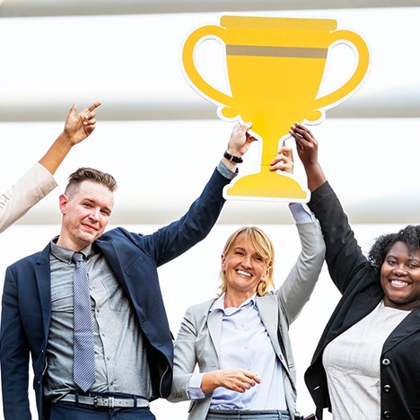 four people hold up a trophy