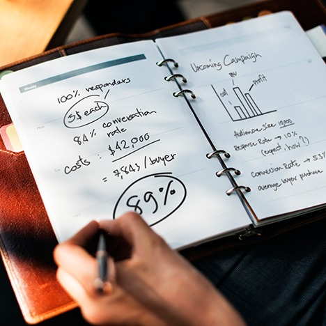 Person taking sales notes in a leather notebook